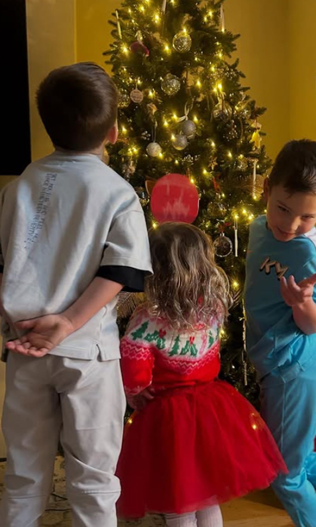 Three children by a Christmas tree