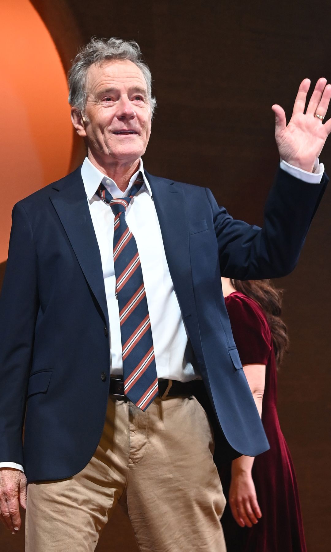 Bryan Cranston waving in a suit and tie