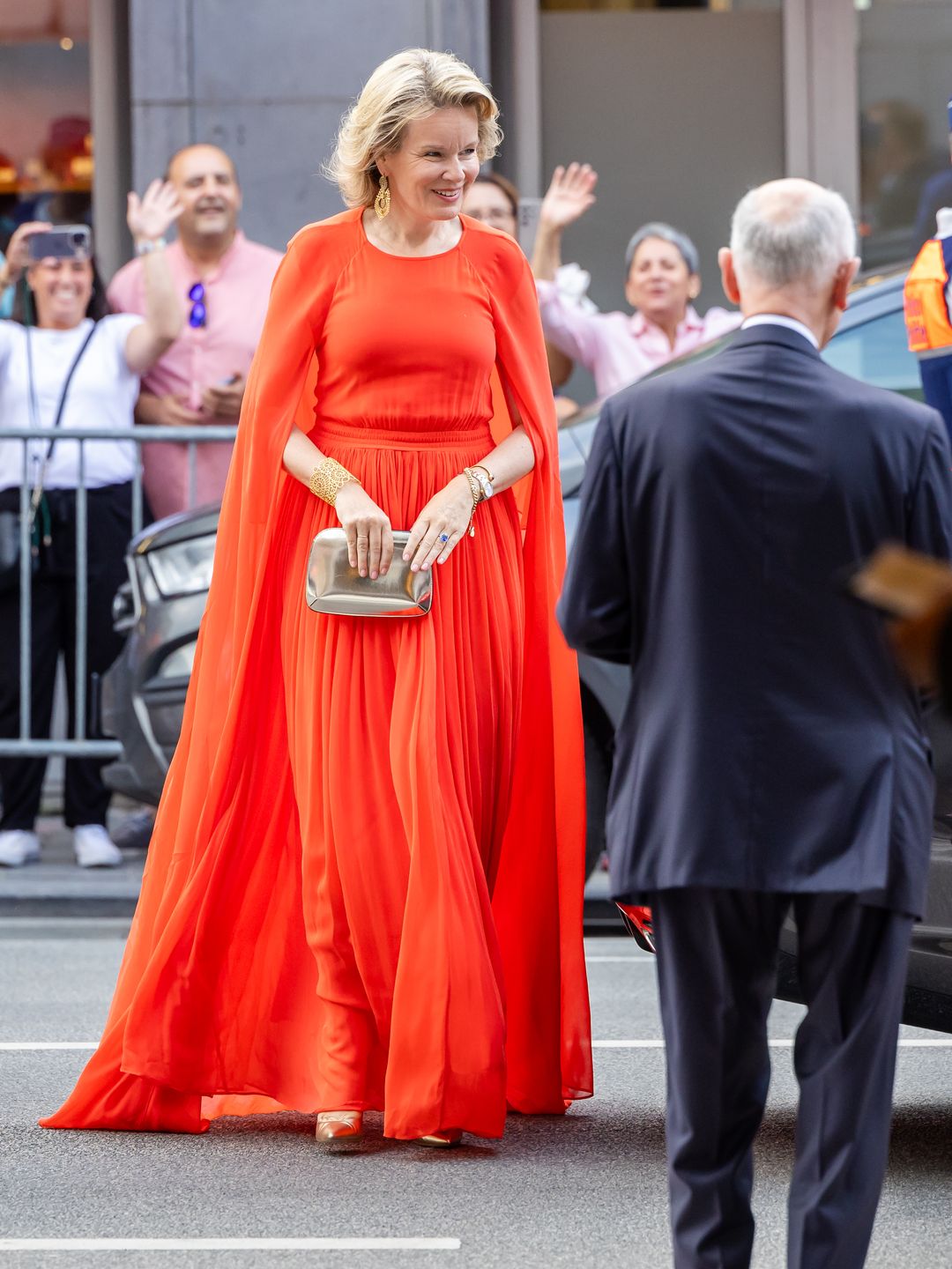 Full-body image of Queen Mathilde in an orange dress