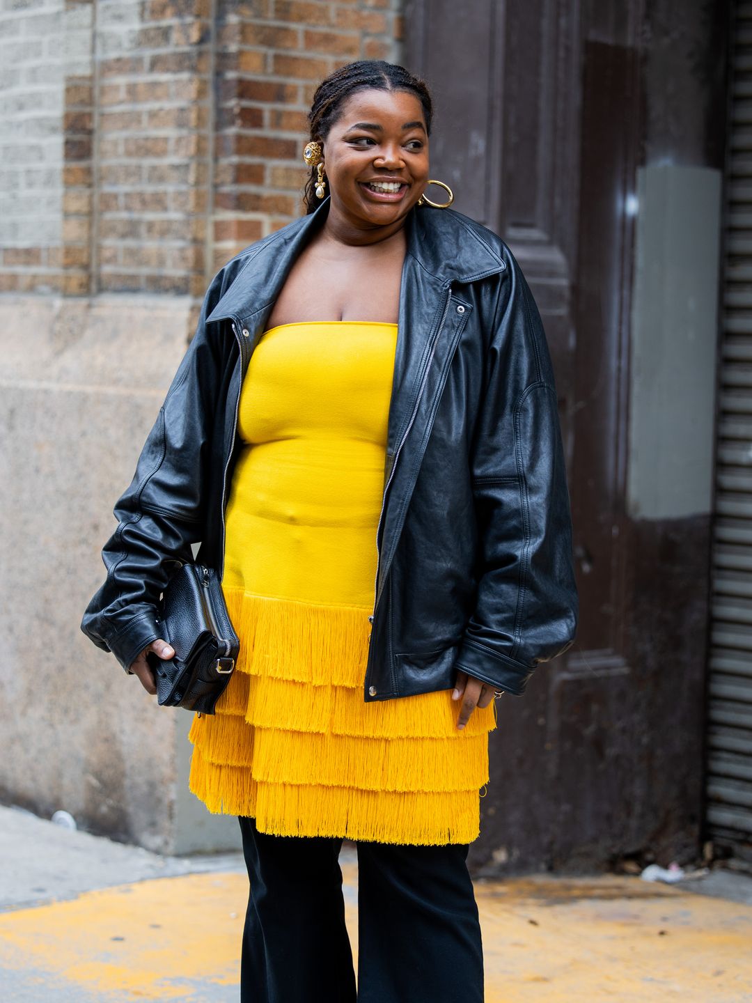 Gabriella Karefa Johnson wears black leather jacket, yellow dress and black pants to NYFW