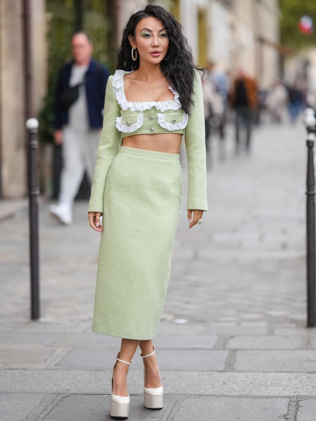 Jessica Wang wears a pale green lace-trimmed crop top with a matching skirt 