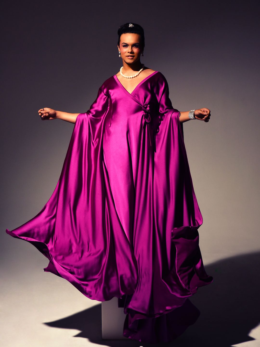 Damian Terriquez posing for a photo in a long silk pink gown