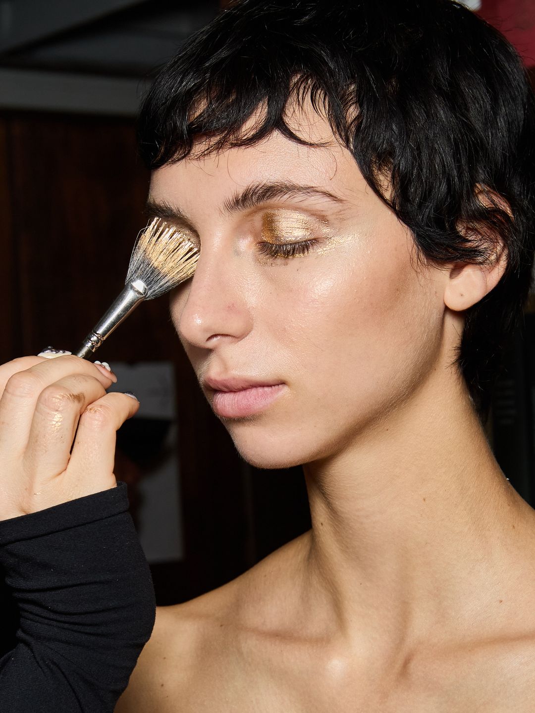 A model gets her makeup done at the Lutz Huelle SS25 show