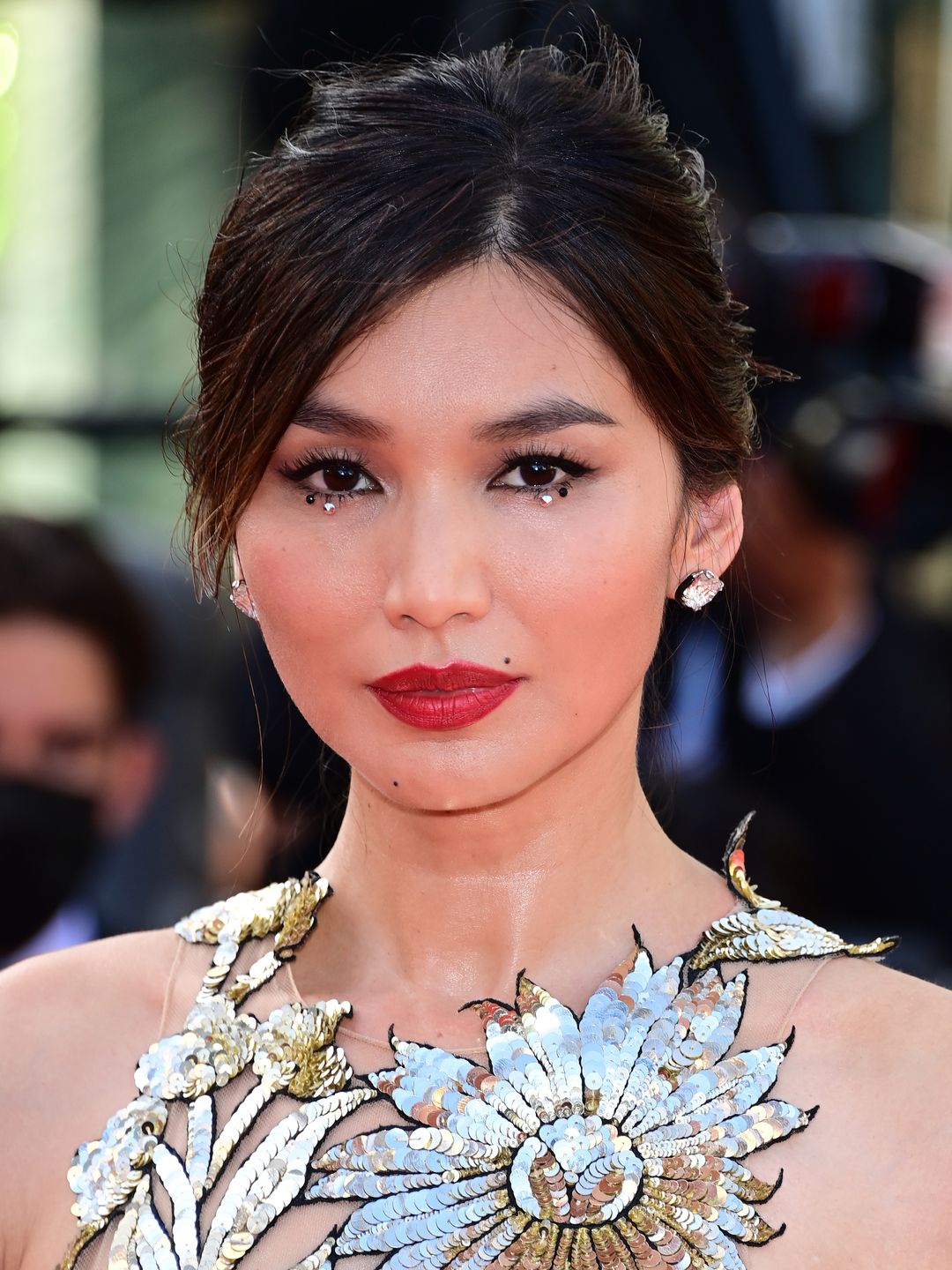 Gemma Chan with a red lip and gem studs under her eyes 