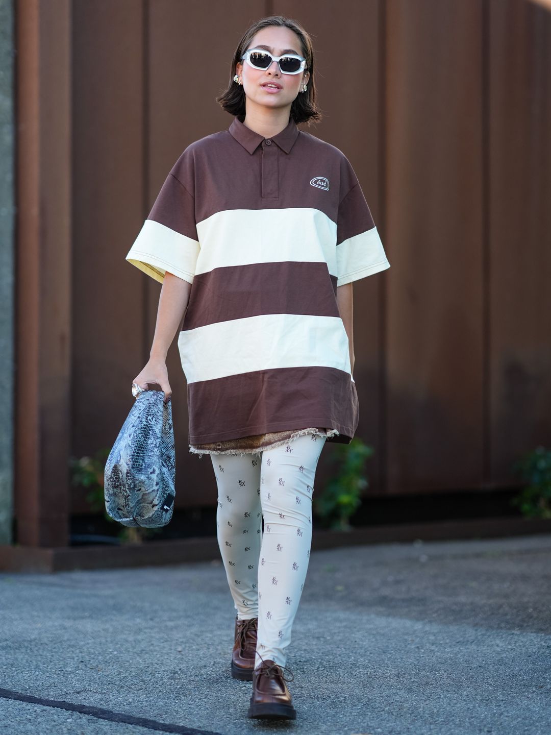 A rugby shirt dress paired with logo leggings and a snakeskin bag outside the Remain show at Copenhagen Fashion Week. 