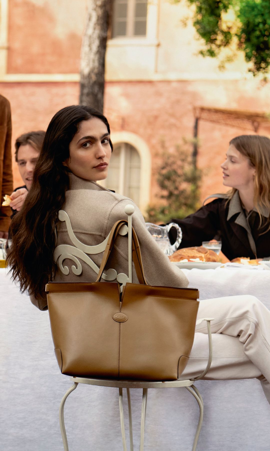 woman in white trousers with large tan toned bag