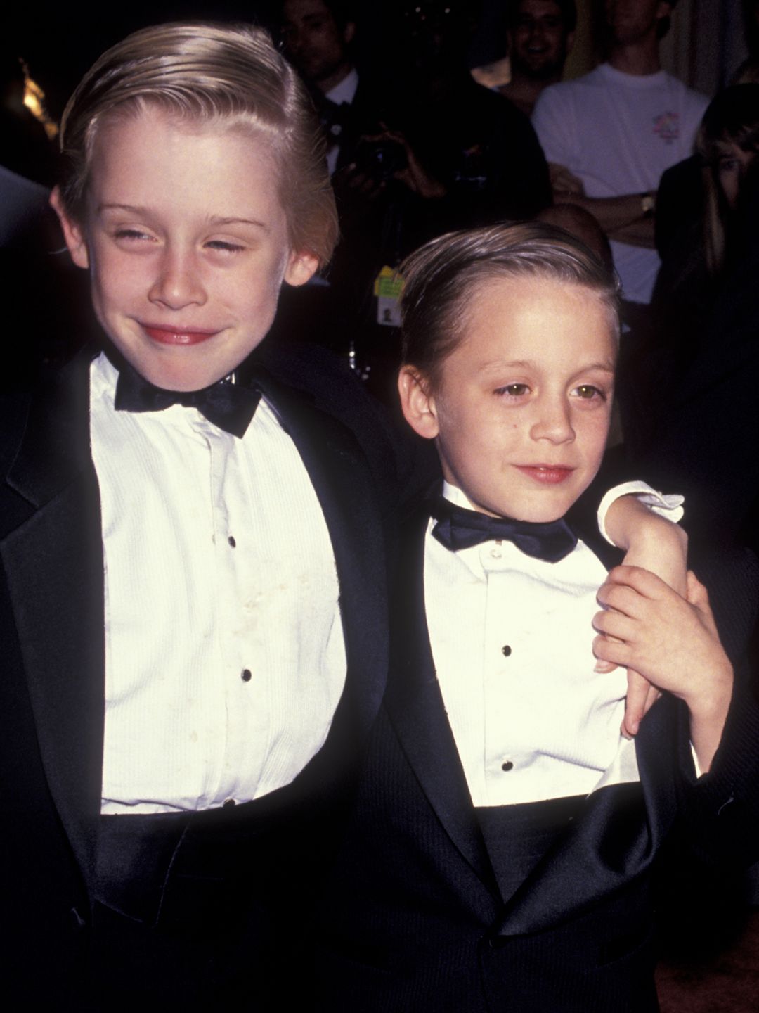 A young Macaulay and Kieran in tuxedos on a red carpet
