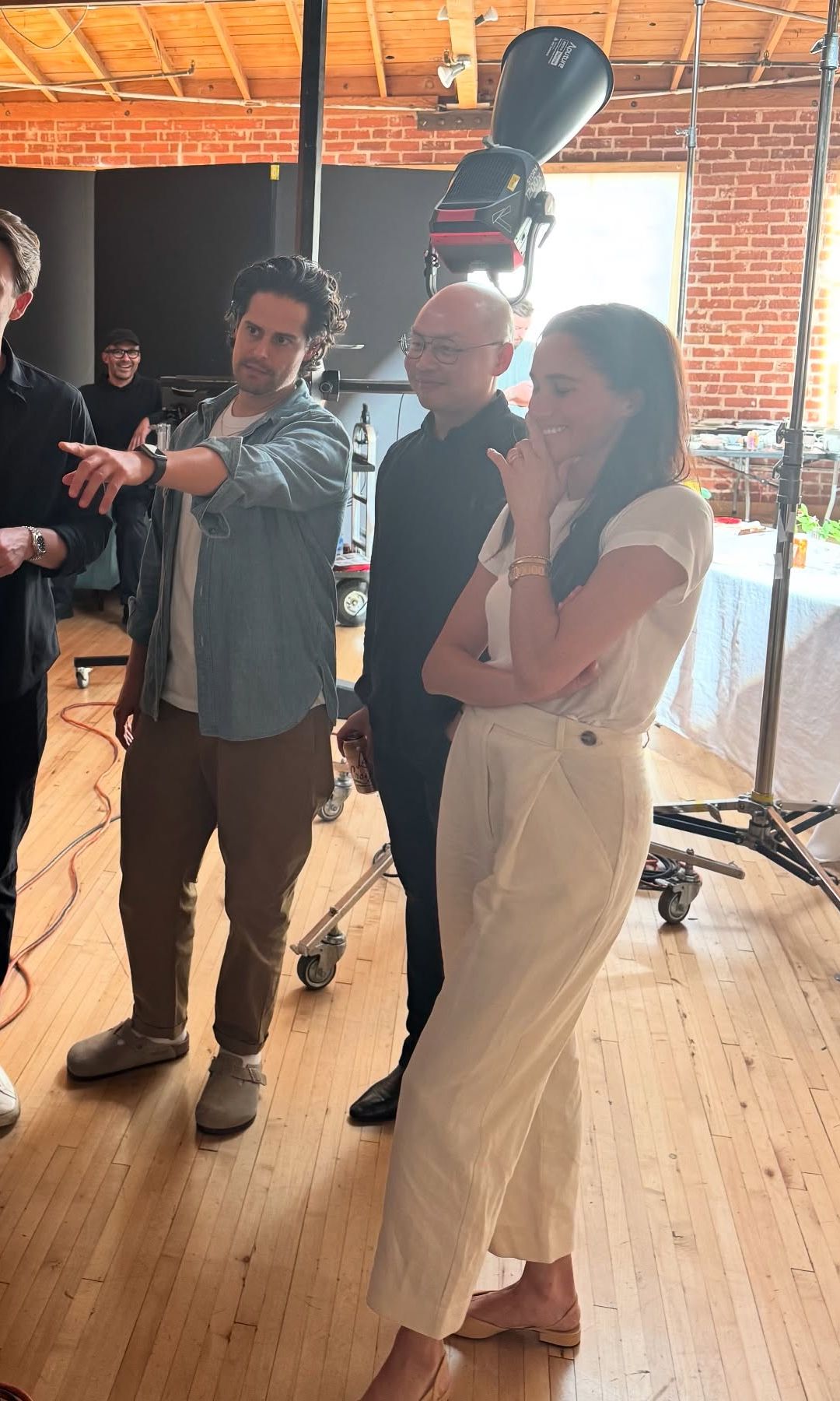 Meghan Markle poses for a photo alongside her team in white trousers and a plain white t-shirt