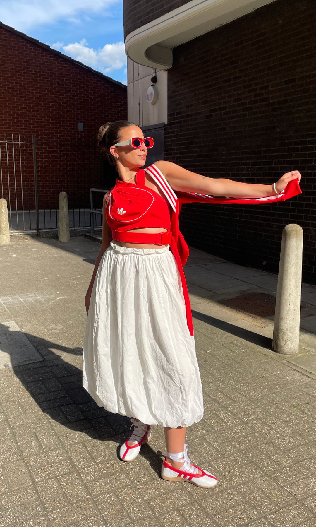 Orion Scott posing in a white skirt and red top