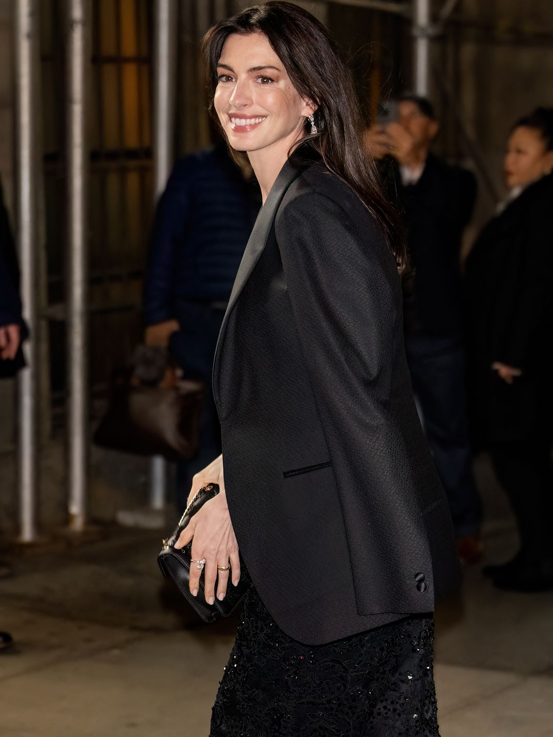 Anne Hathaway wears a black blazer over her halter neck gown 