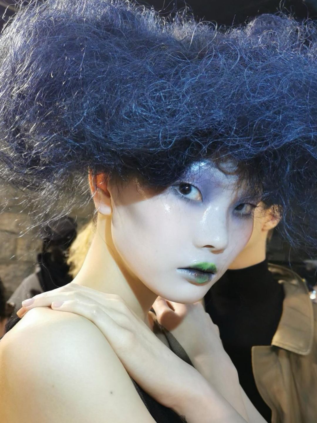 A model wears a blue hat with blue eyeshadow on the catwalk of the Maison Margiela show 