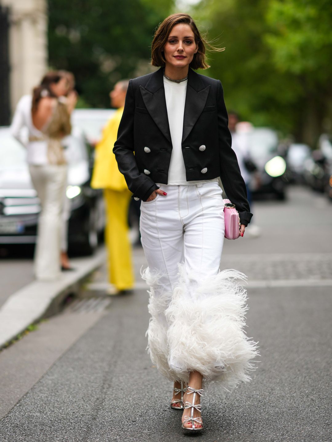 Olivia Palermo wearing a black blazer over a white jumper with feathered white jeans 