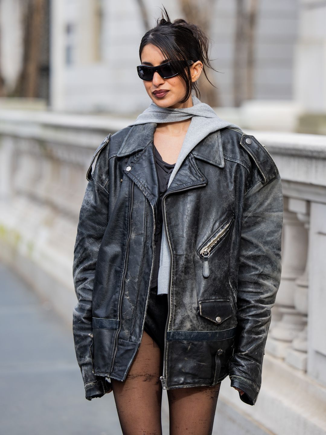 A guest wears oversized leather jacket, tights outside Coach's NYFW show