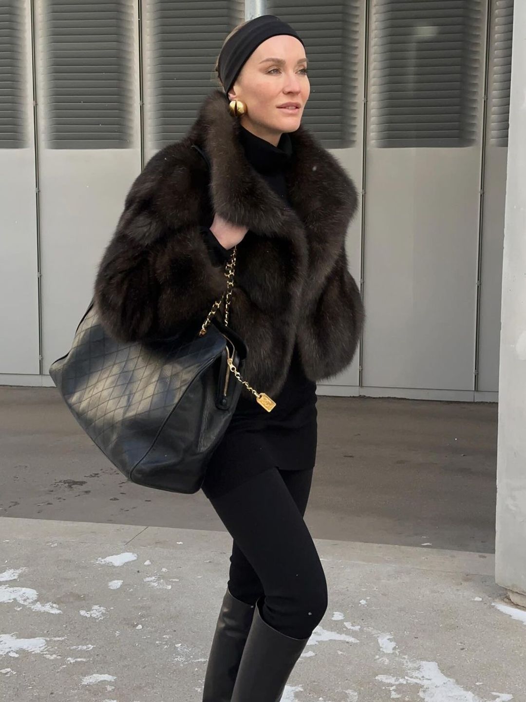 Instagram style mogul @tetyamotya wears a brown fur coat over a black mini dress and tights for a walk in the snow