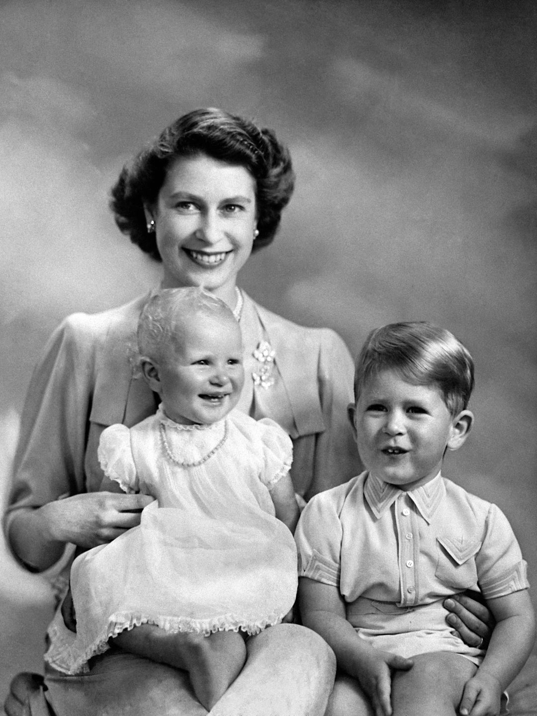 A young Queen Elizabeth with her children known then as Prince Charles and Princess Anne on her 1st birthday