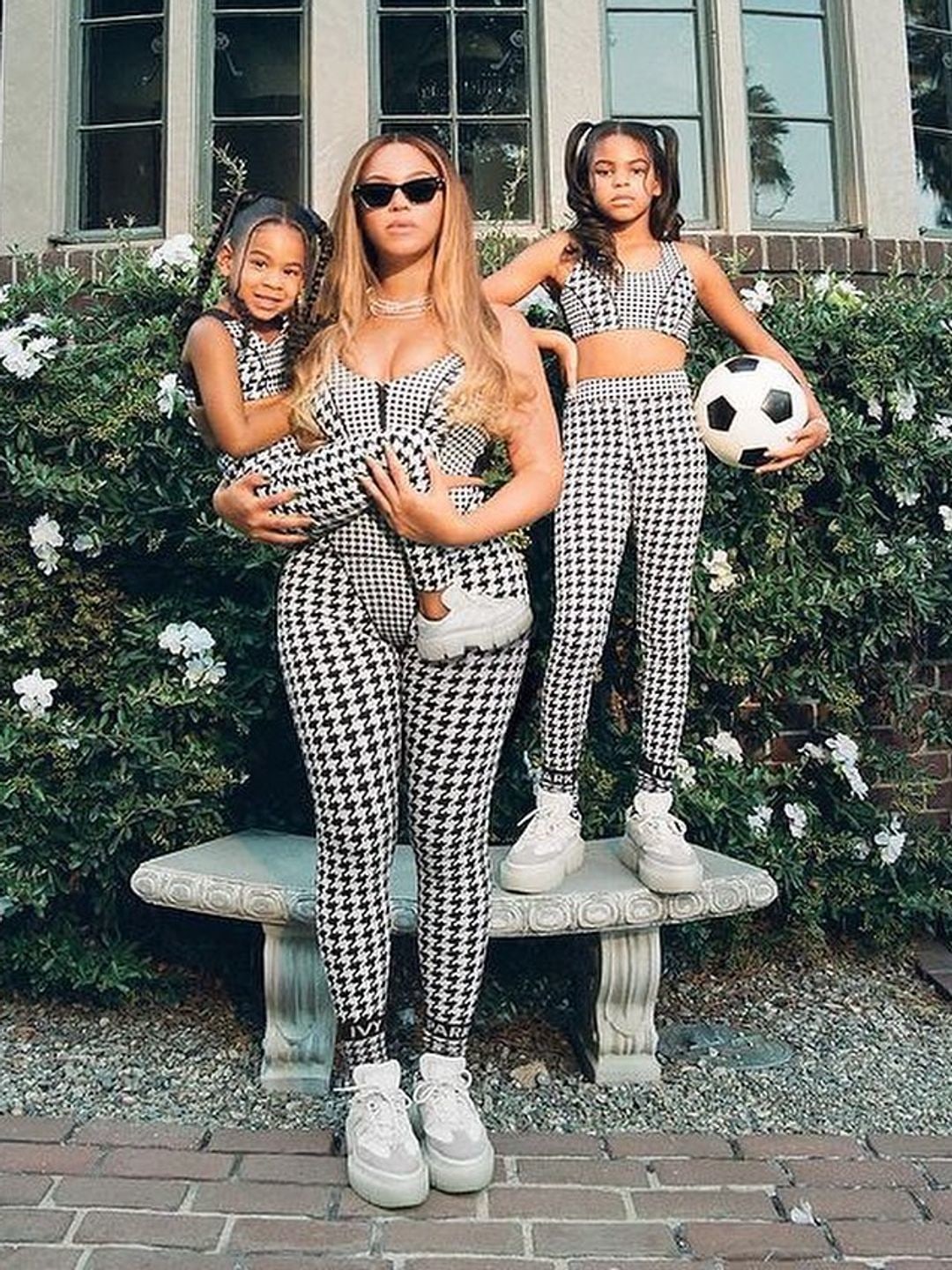 Beyonce stood in a garden with Rumi in her arms and Blue Ivy stood with a soccer ball behind her
