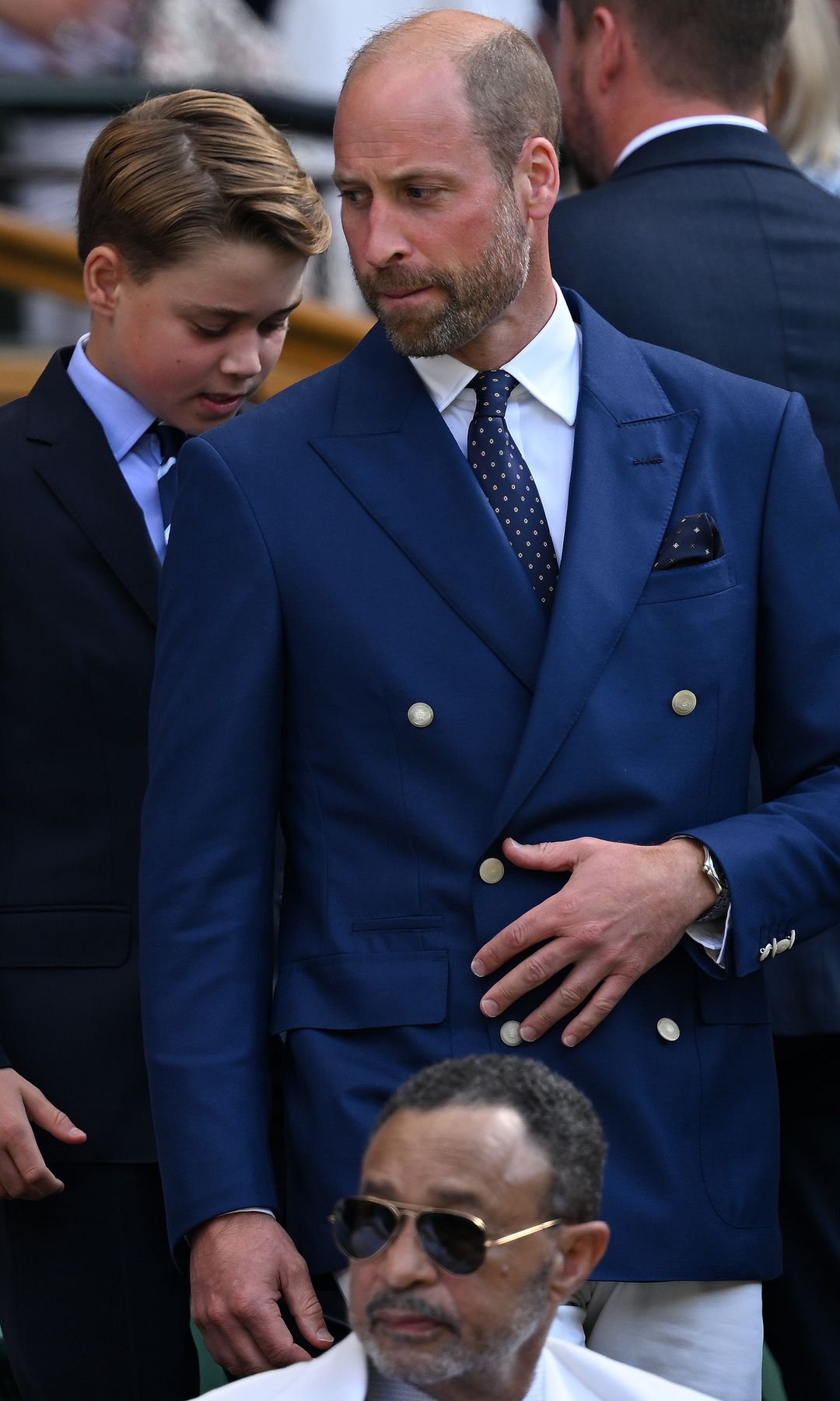 Prince William biting his lip with Prince George in the background