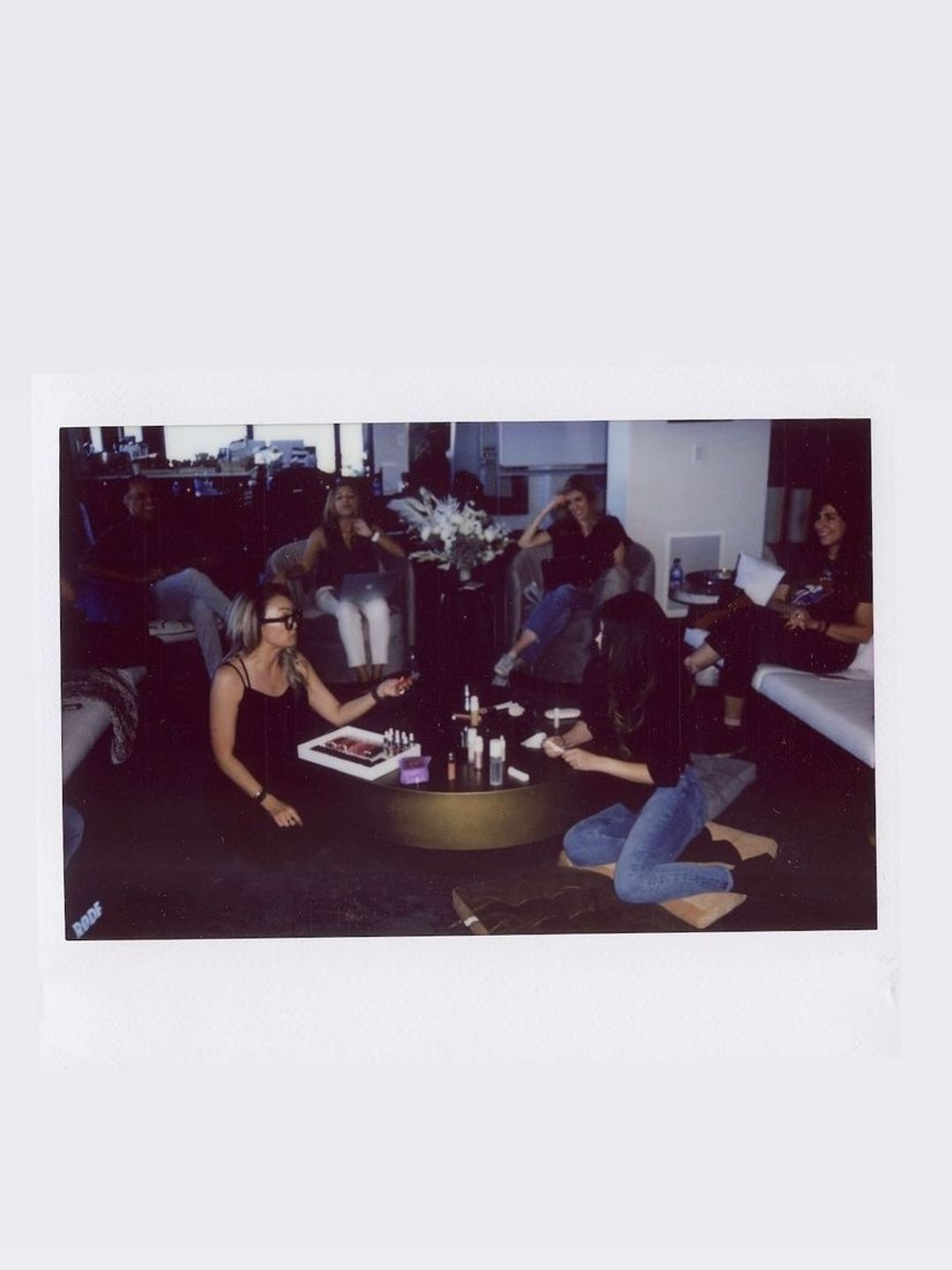 Selena Gomez kneeling looking at products with her team 