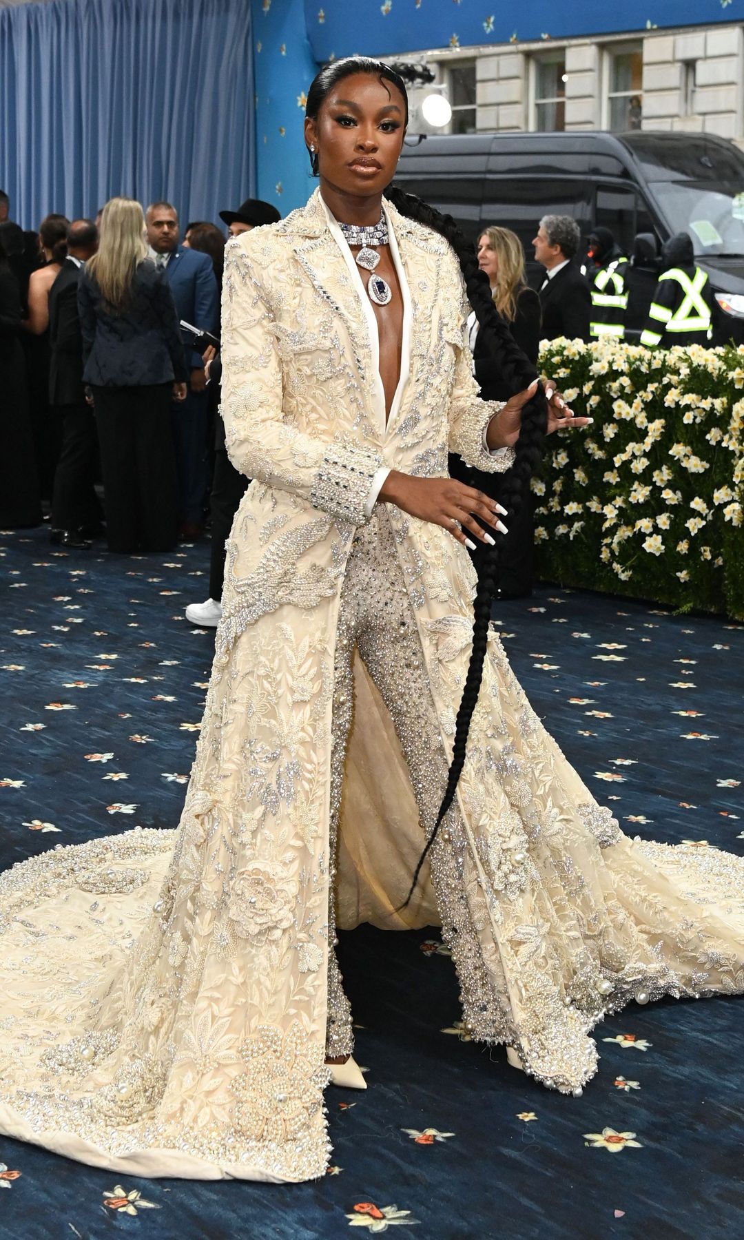 Coco Jones wears a cream and silber embellished coat dress and matching glittering trousers.