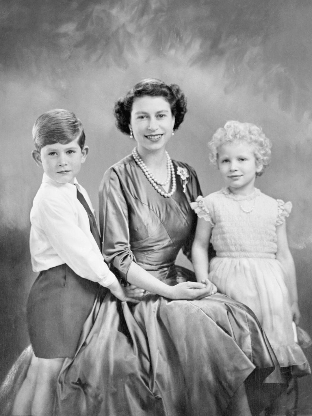 A black-and-white photo of King Charles and Princess Anne with the Queen