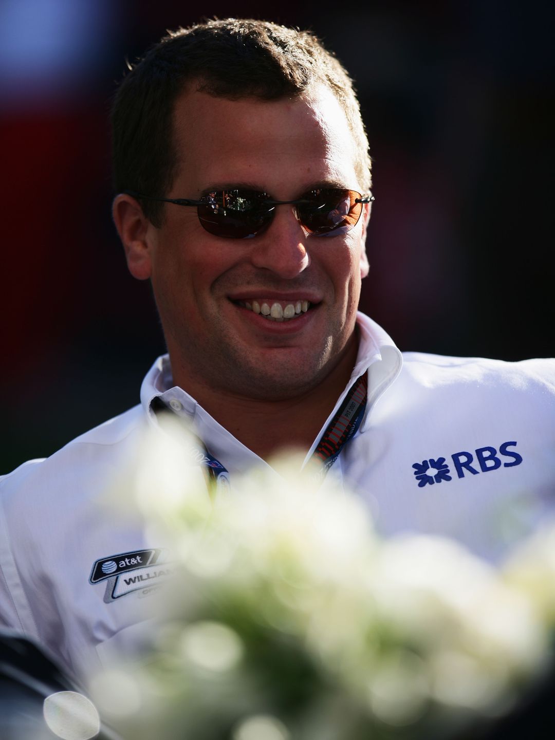 Peter Phillips smiling in a white sports shirt and sunglasses