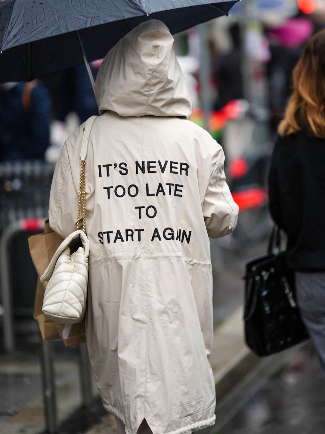  A guest wears a white latte with embroidered black "it's never too late to start again" embroidered slogan long hoodie coat, a white latte puffy leather shoulder bag from Saint Laurent Paris, outside Salvatore Ferragamo, during the Milan Fashion Week 