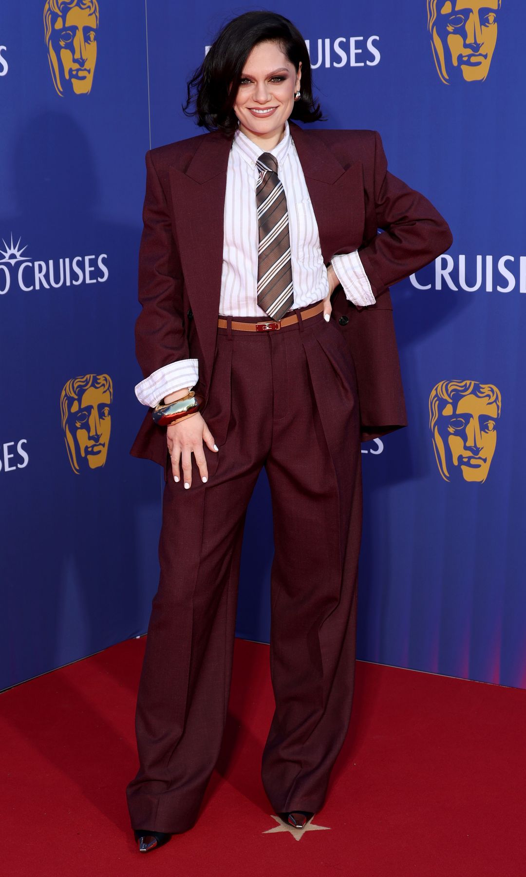 Jessie J in a deep red suit and tie on the red carpet