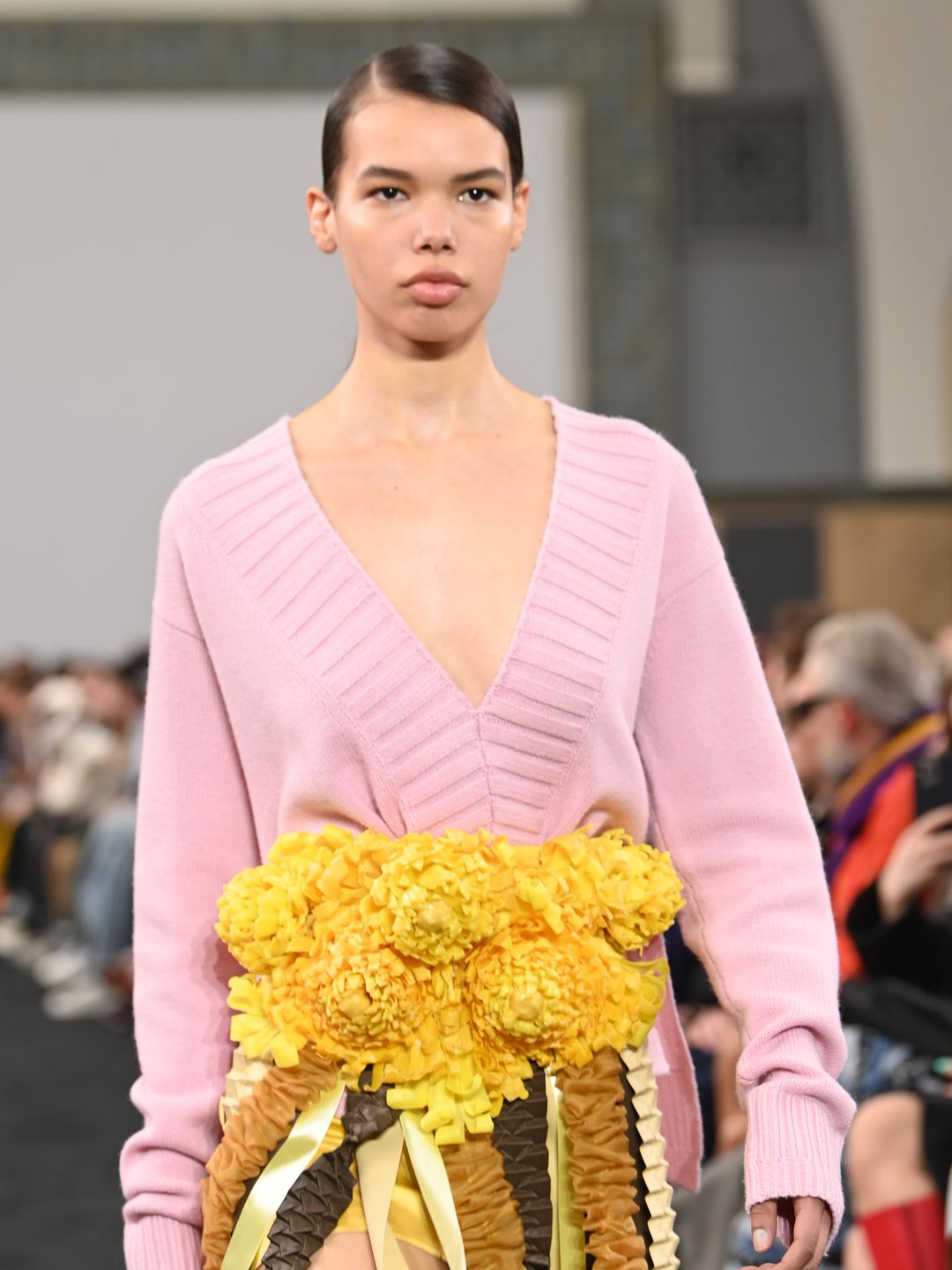  A model walks the runway at the JW Anderson show during London Fashion Week wearing a pink v neck cardigan adorned with yellow flowers