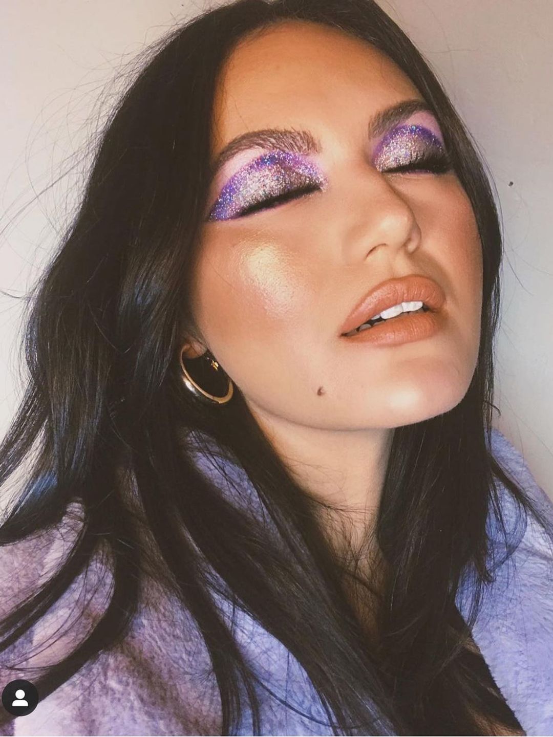 Woman with disco sparkle purple eye makeup 