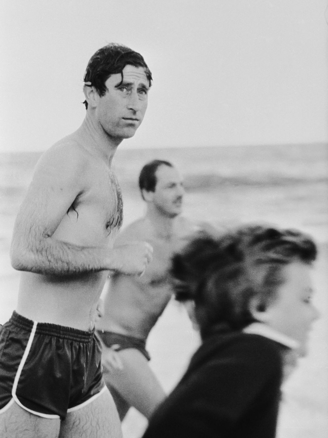 charles running along beach in swimming trunks