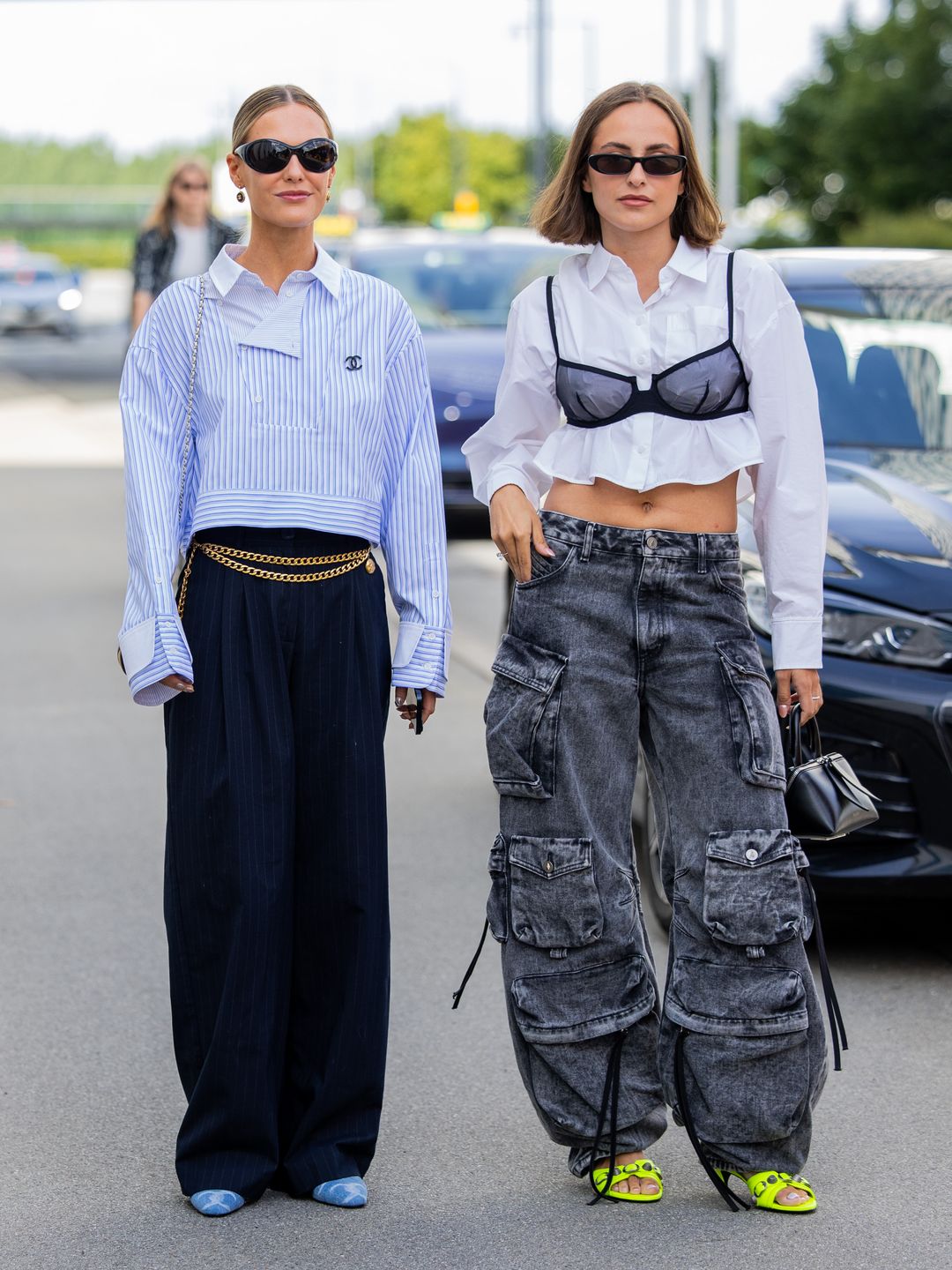 Tine Van Cauwenberghe wears blue white striped Chanel shirt, navy pants & a guest wears black bra, white cropped button shirt, wide leg grey jeans with side pockets outside Munthe during Copenhagen Fashion Week. 