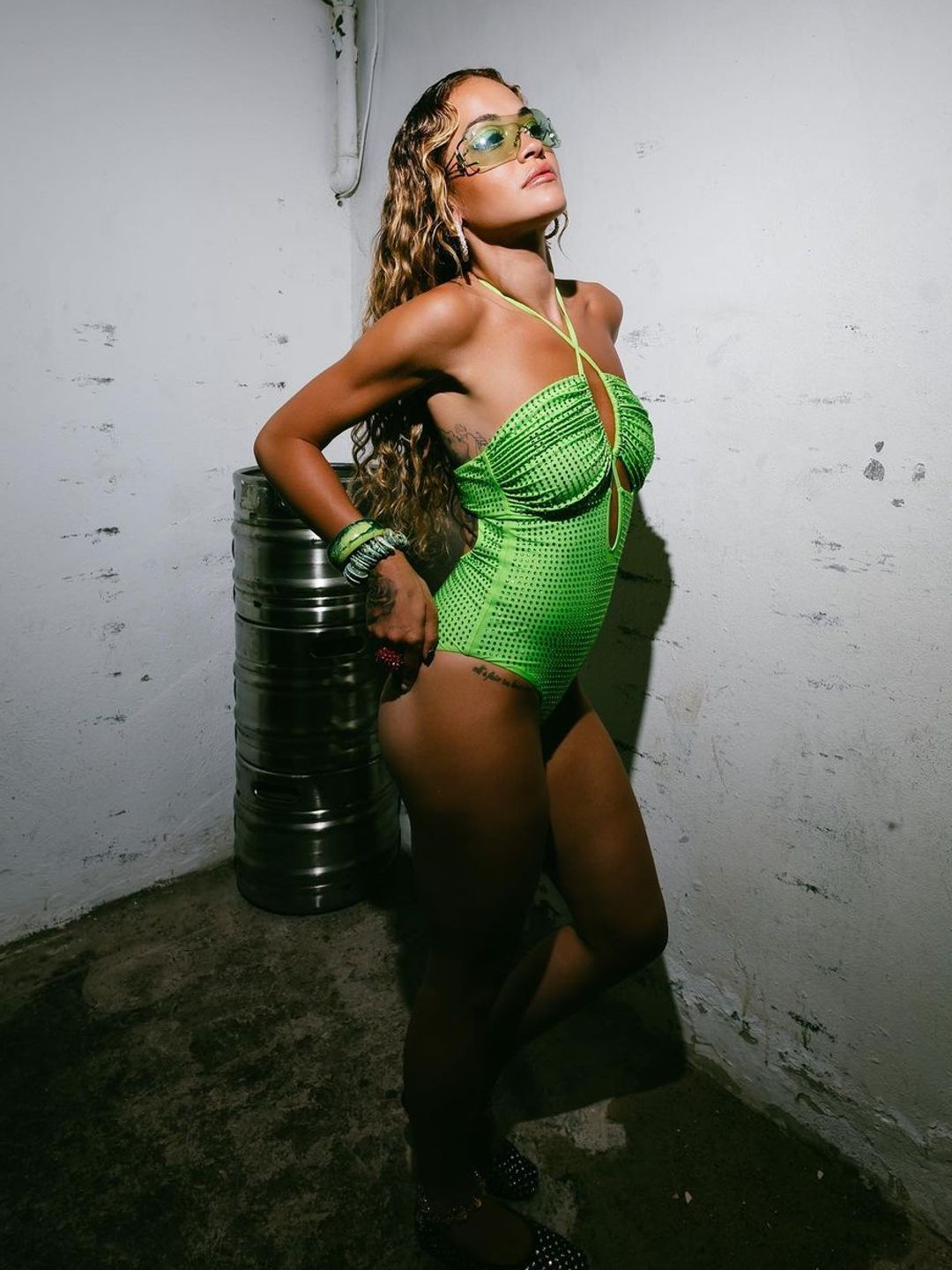 Rita Ora poses in a green swimsuit before performing on stage