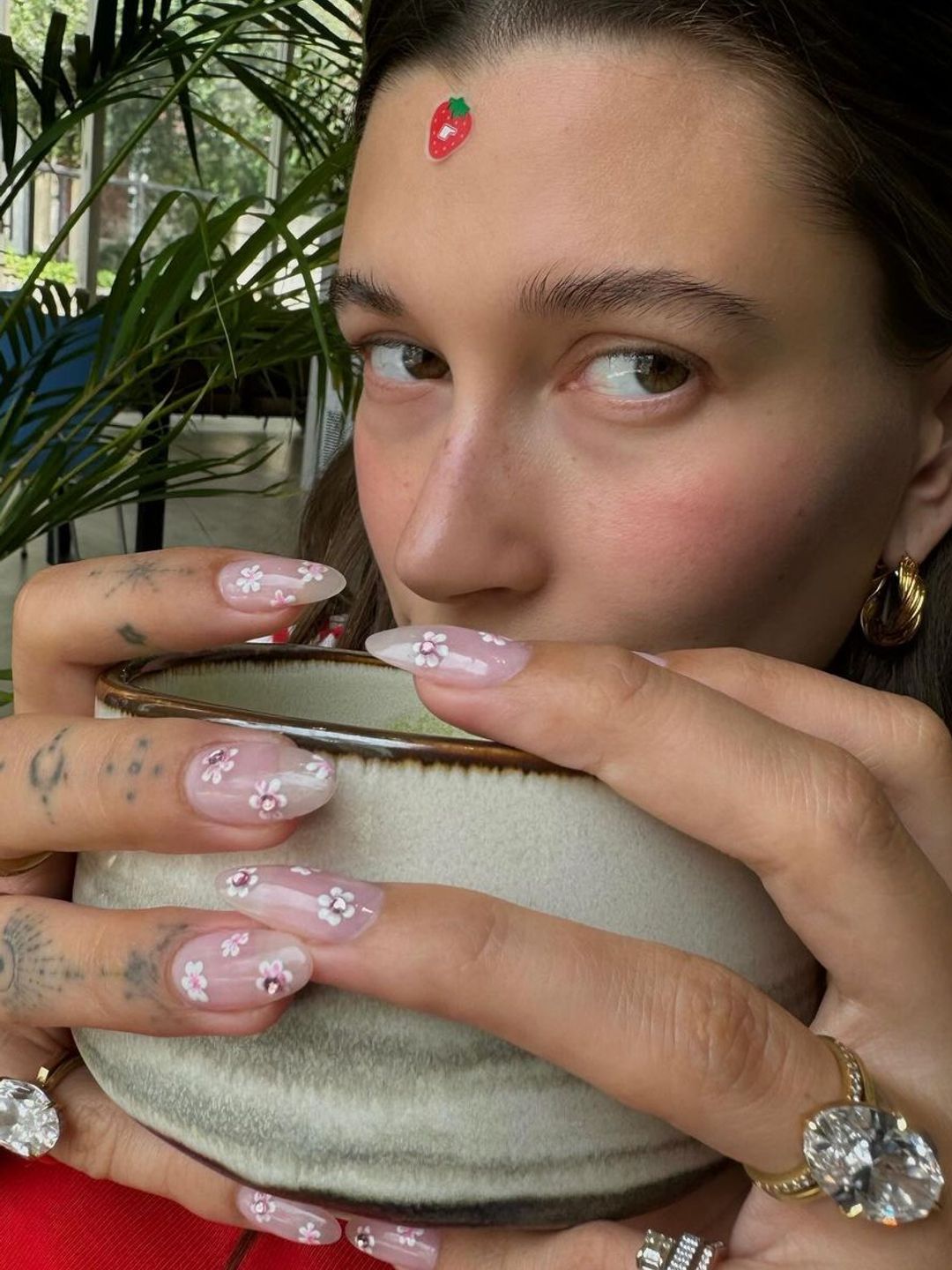 Hailey Bieber holding a cup with a blossom manicure 