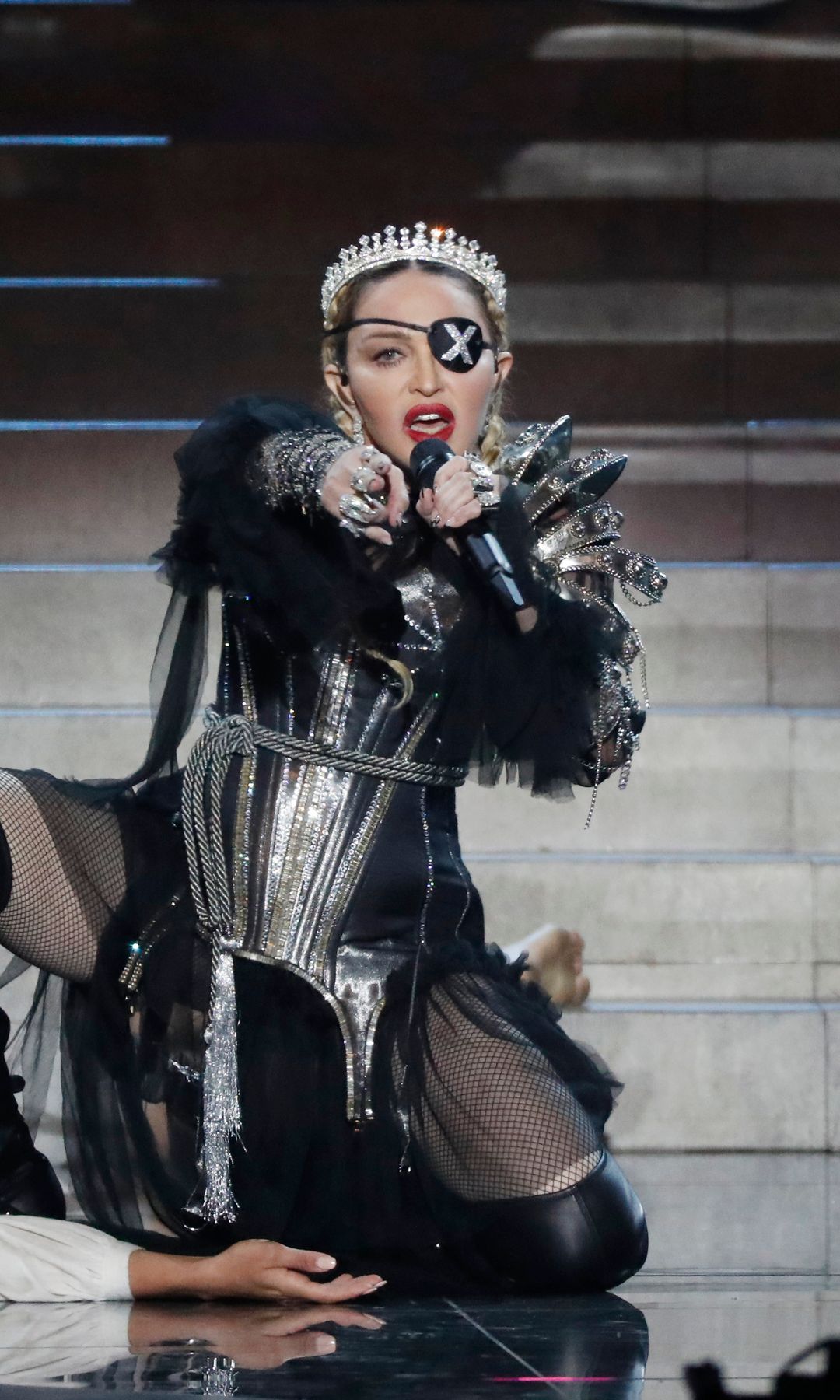 Madonna performs at Eurovision in a Gaultier silver corset, fishnets, an X-eyepatch and crown, creating a cyber-medieval rebel queen look.