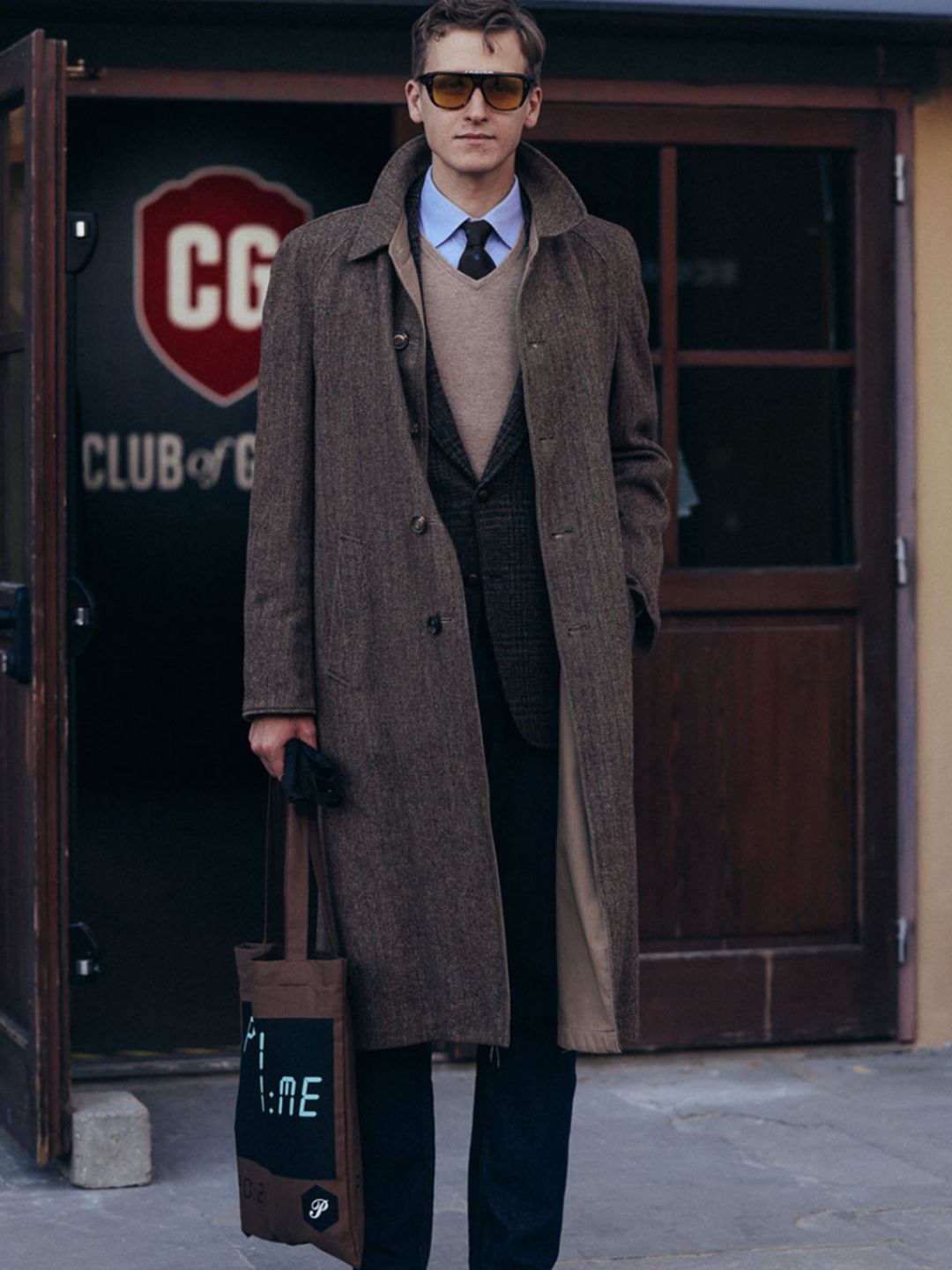 A guest outside Pitti Uomo in Florence wears a brown overcoat and suit combo