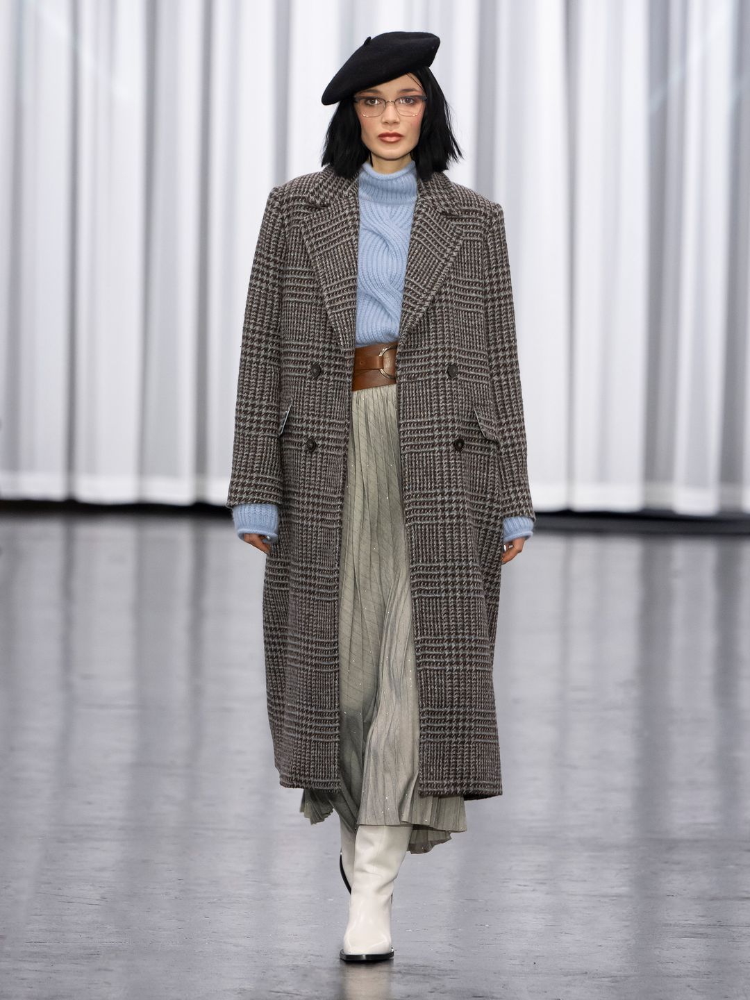 Marc Cain model wears a baby blue sweater, pleated maxi skirt, over coat and beret on the runway