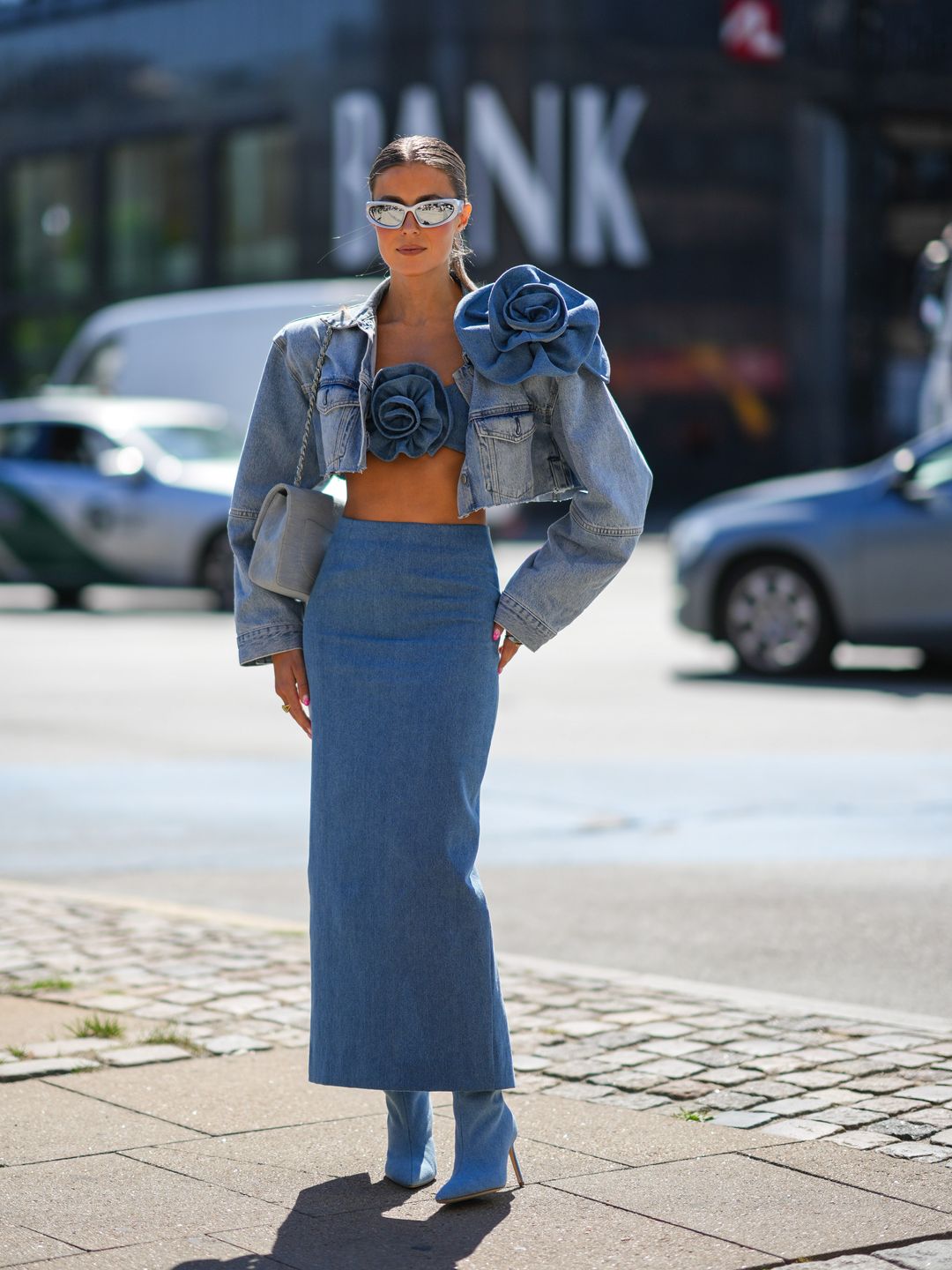 A Fashion Week guest styles a rosette-adorned micro top with a cropped jacket and a midi skirt 