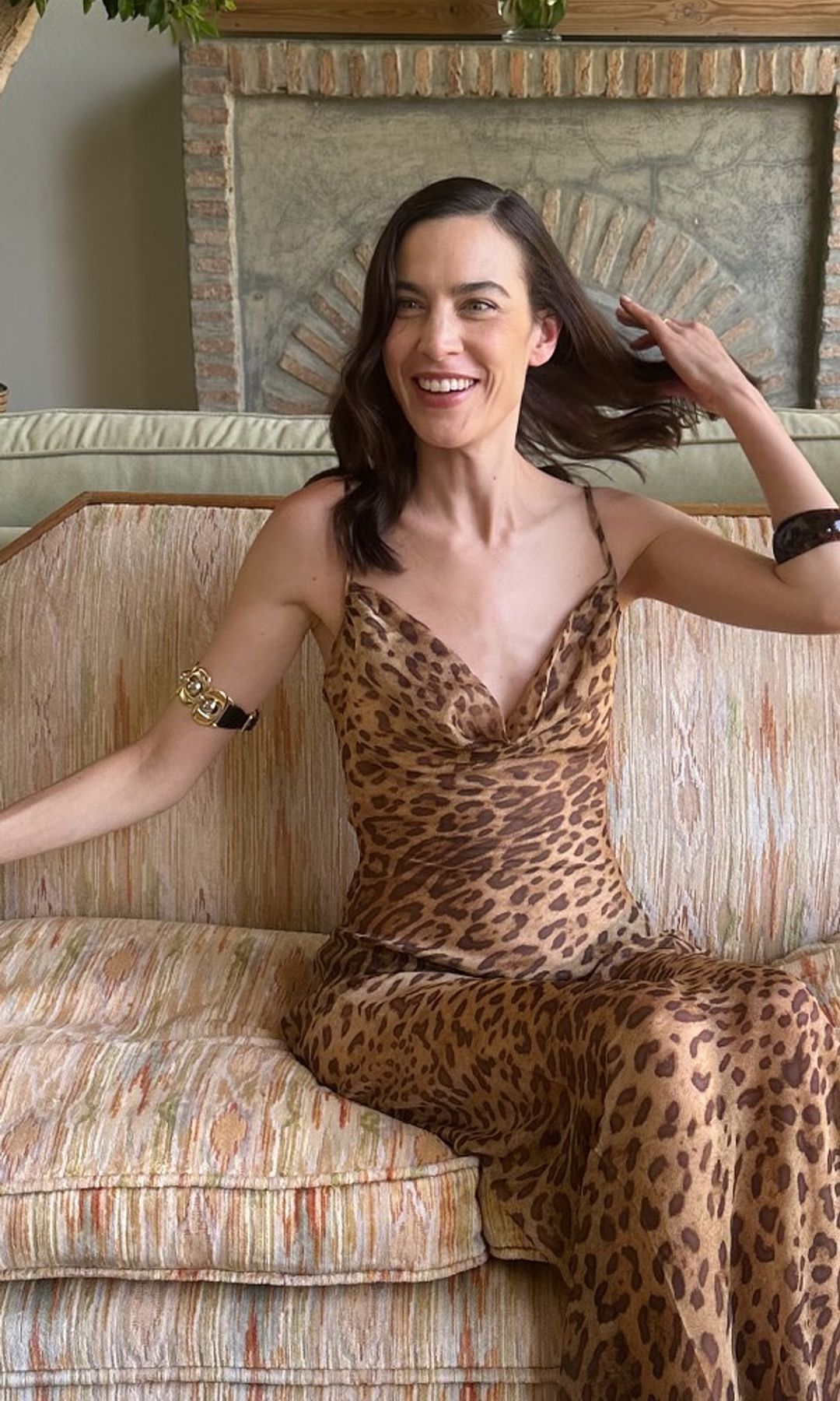 Alexa Chung poses in a leopard print sheer dress on a couch
