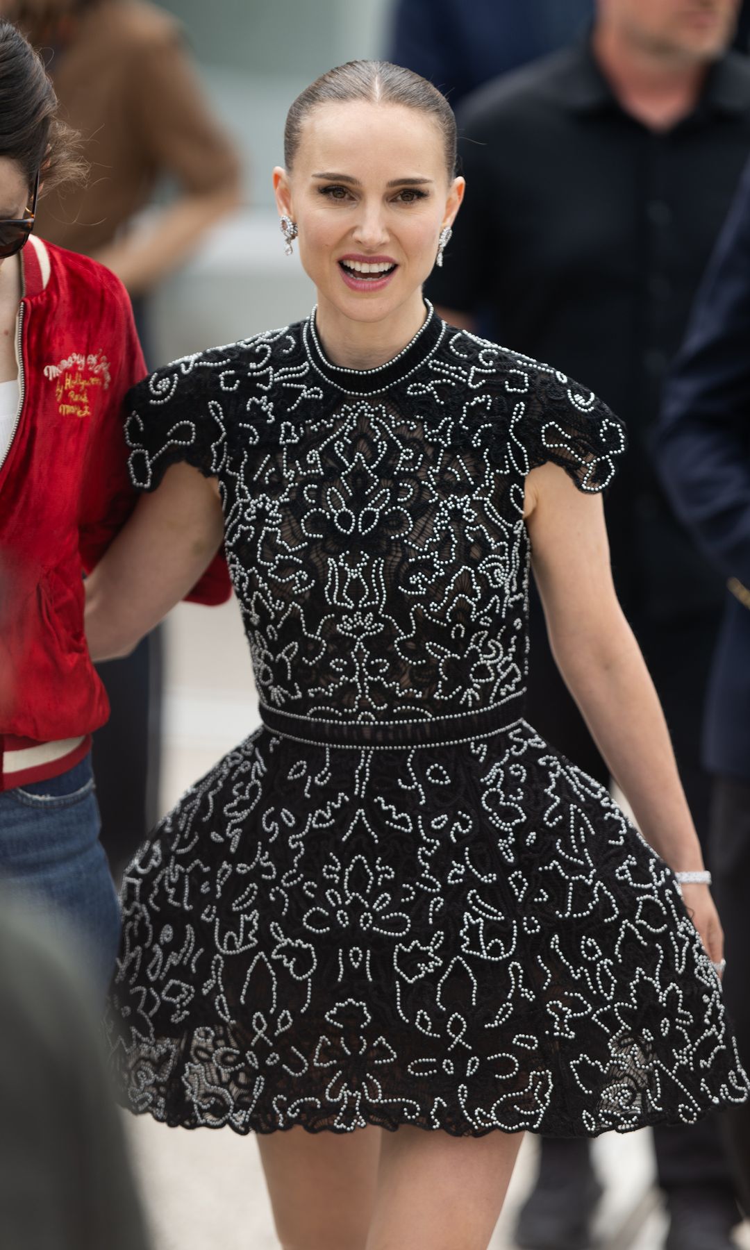 Natalie Portman smiling in a black dress with white squiggles on it