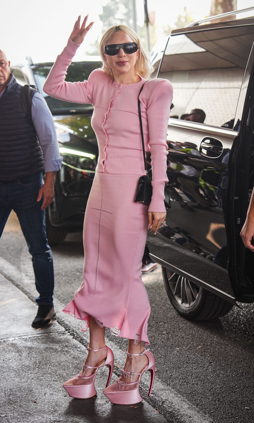 Lady Gaga arrives at Milan airport after 2 days of the filming of "The Devil Wears Prada 2" in a baby pink knitted set