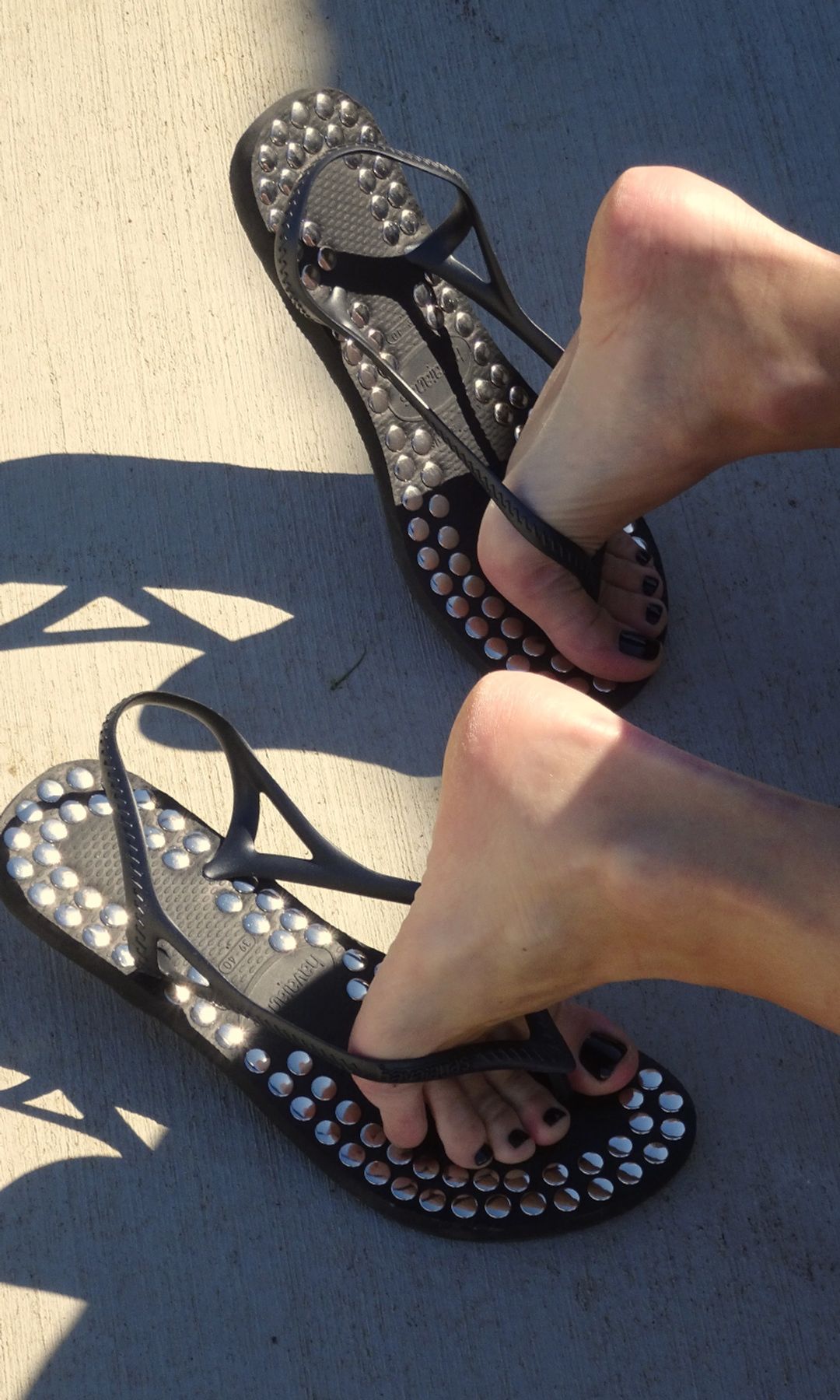 A close up shot of a model wearing studded flip flops