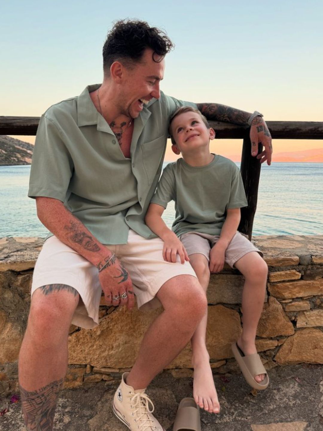 Danny Jones sitting on a wall with his young son