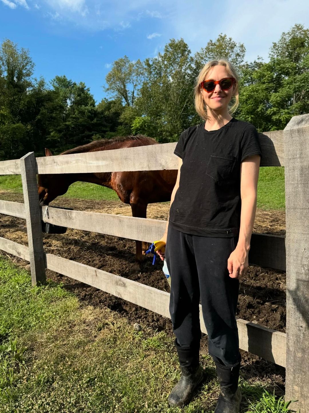 Amanda Seyfried poses with her horse in track pants and a black t-shirt