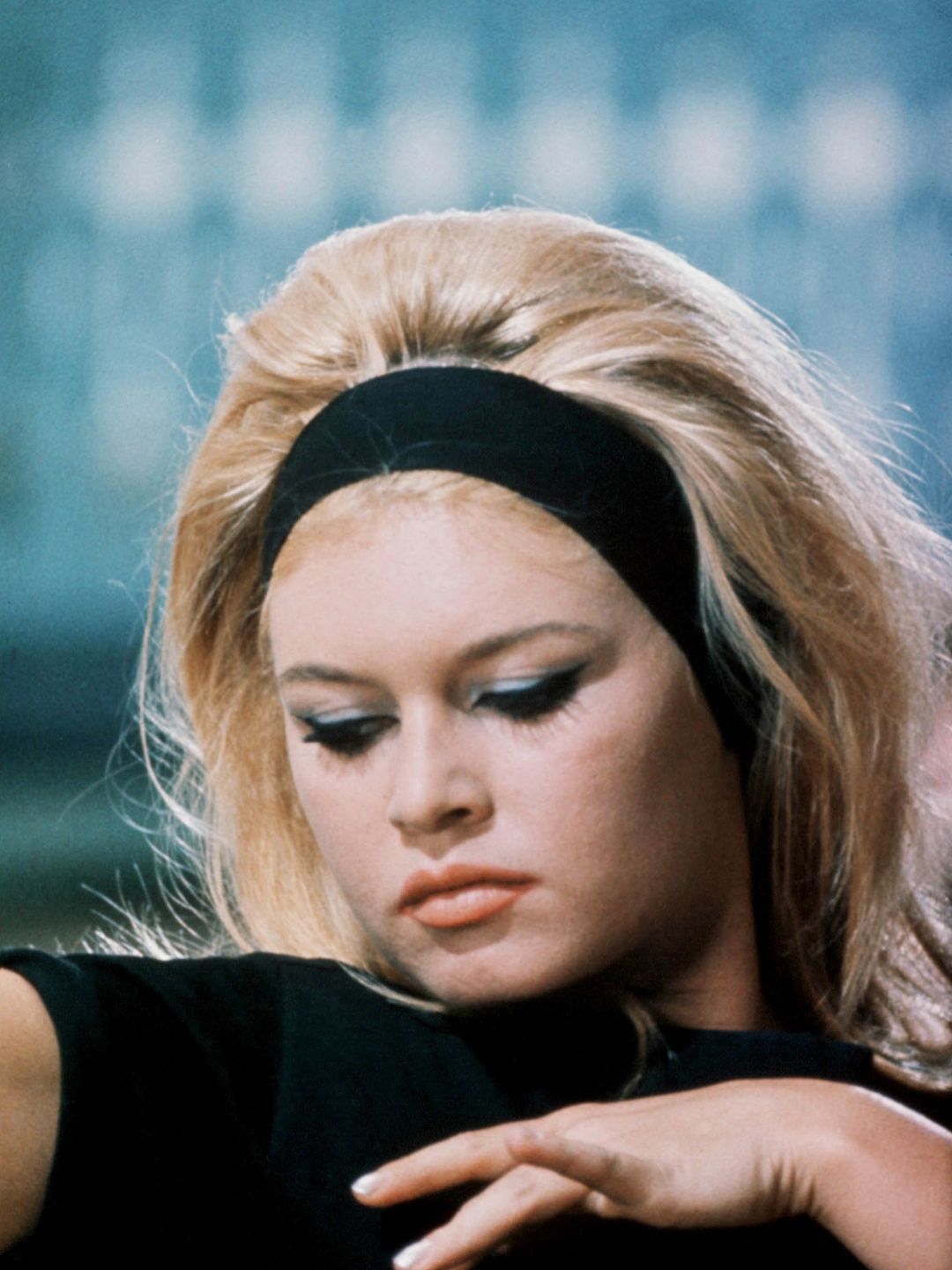 French actress Brigitte Bardot on the set wearing a thick black headband and blue eye makeup 