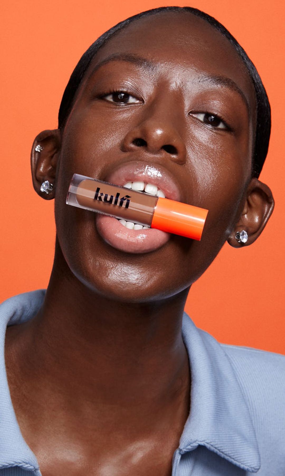 A model with a concealer placed between her lips 