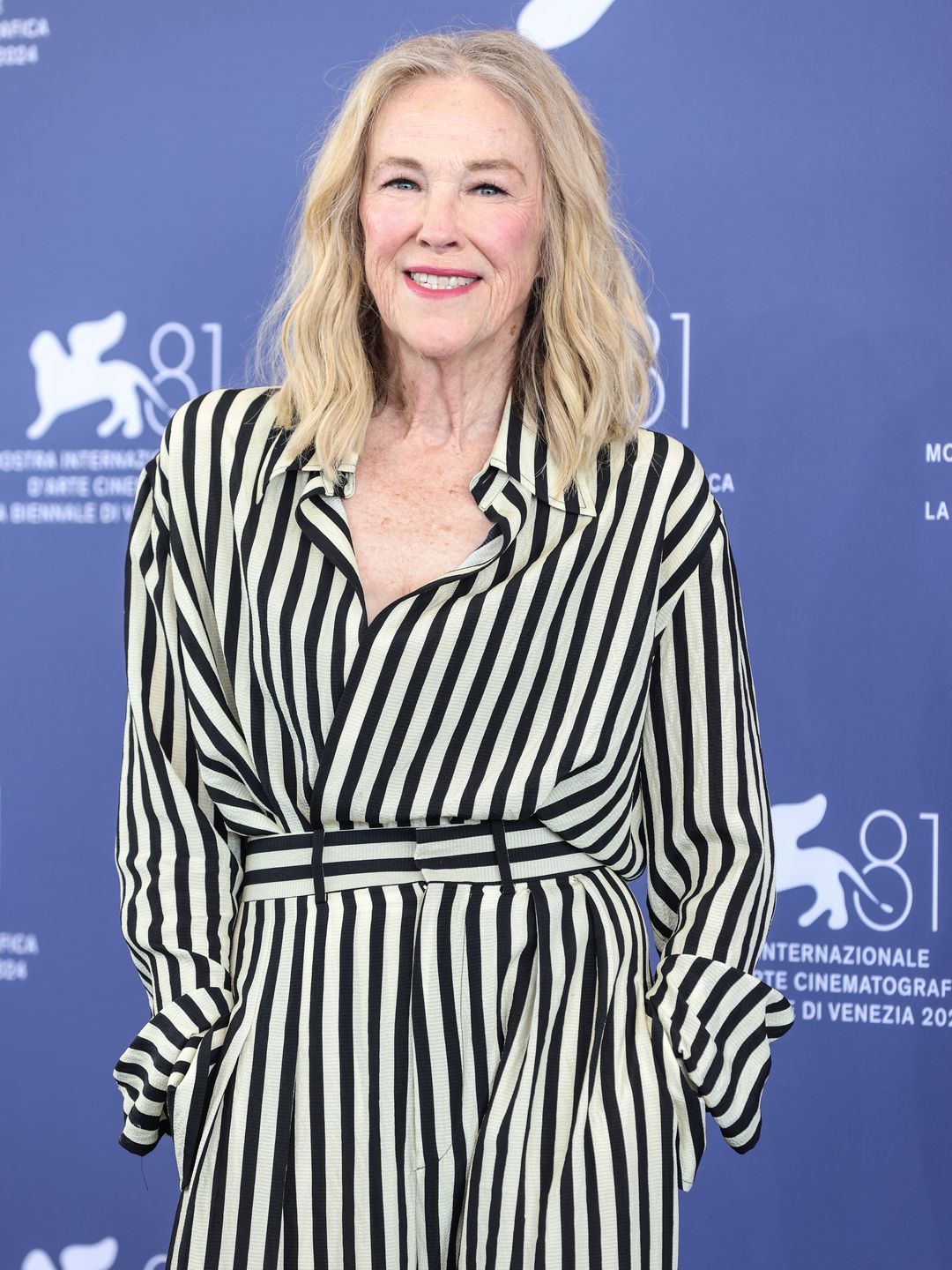 Catherine O'Hara em um vestido listrado preto e branco