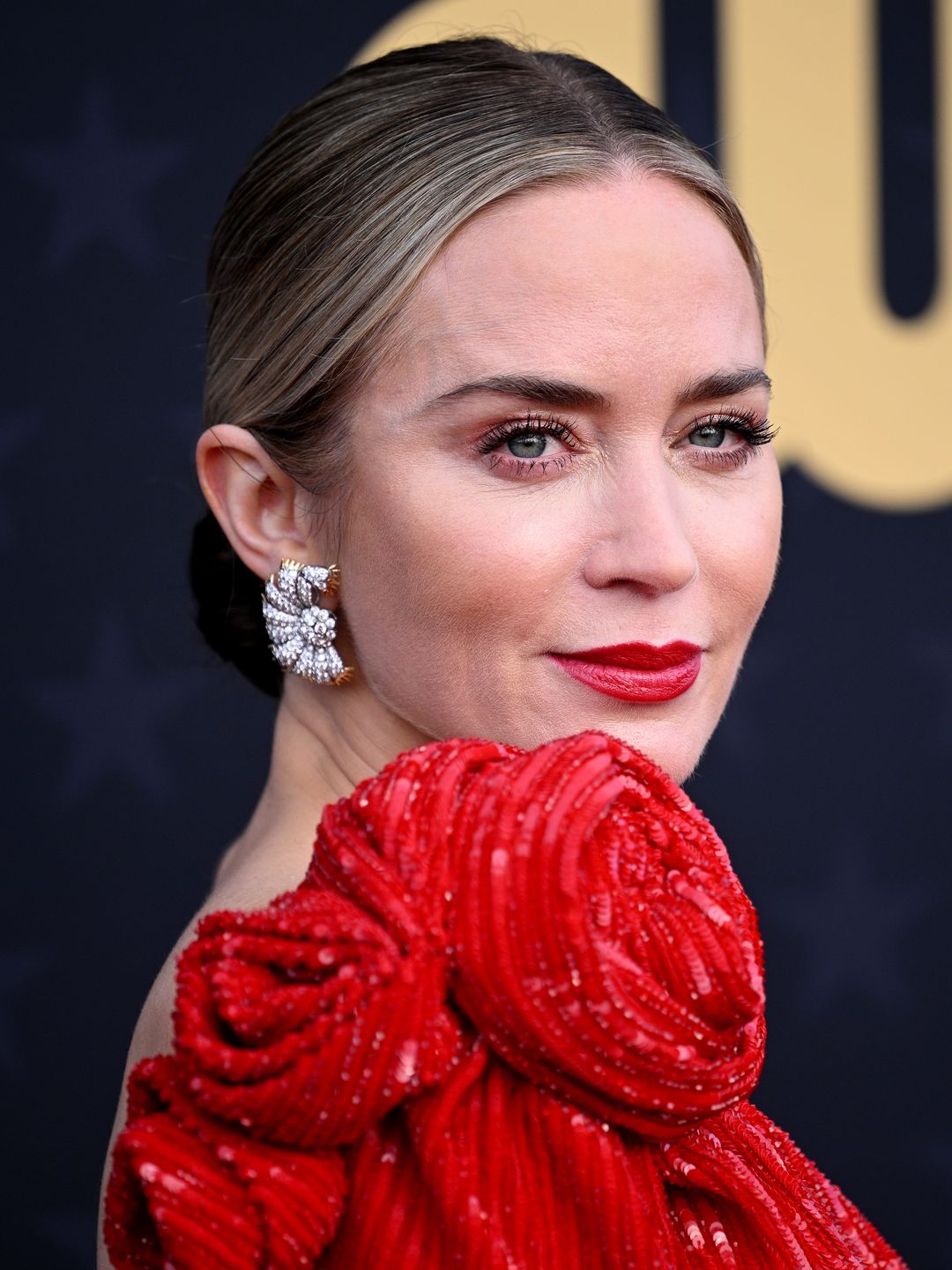 Emily Blunt wearing a rose-adorned dress on the red carpet 