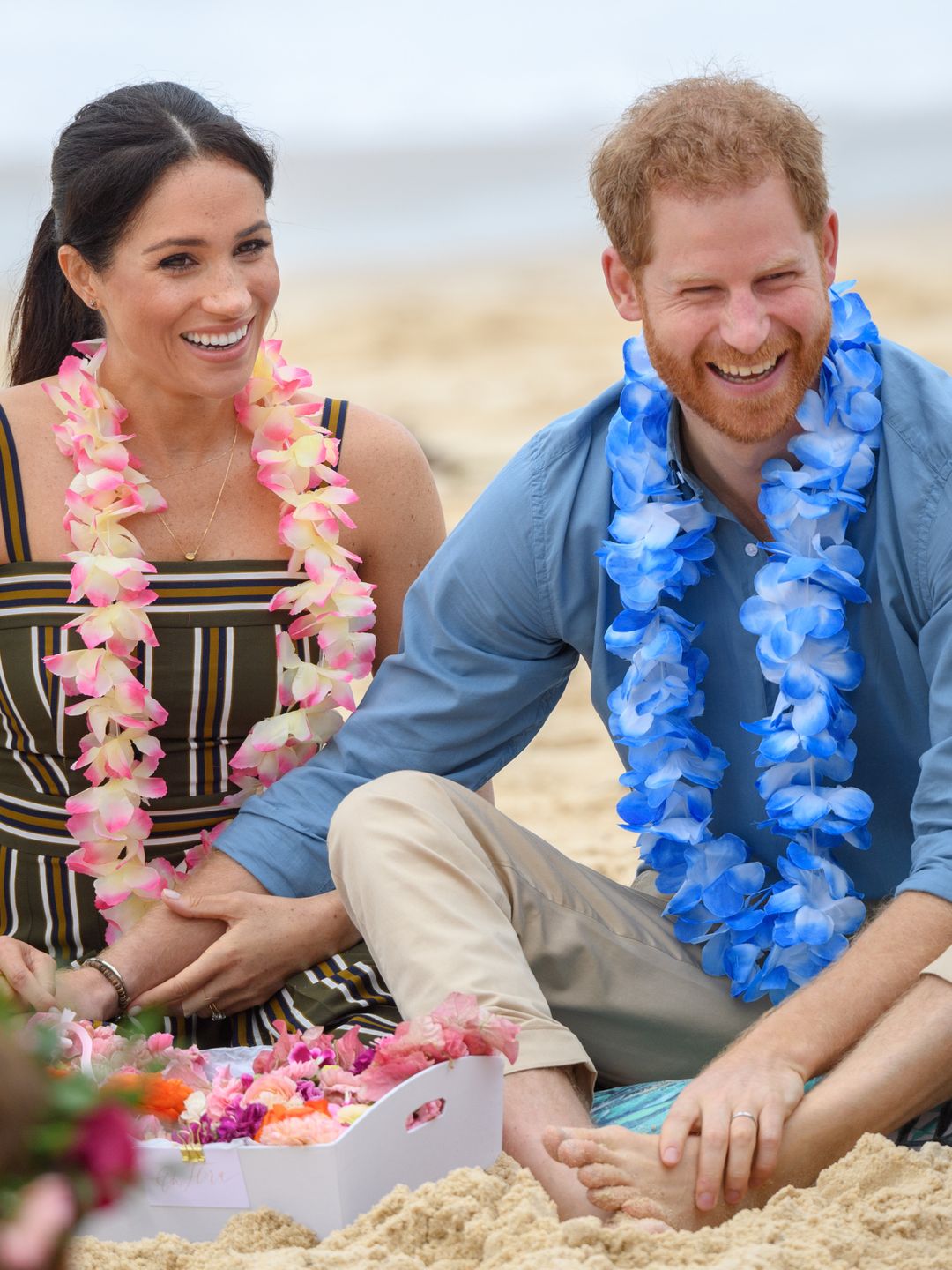 harry and meghan sitting on beach in australia