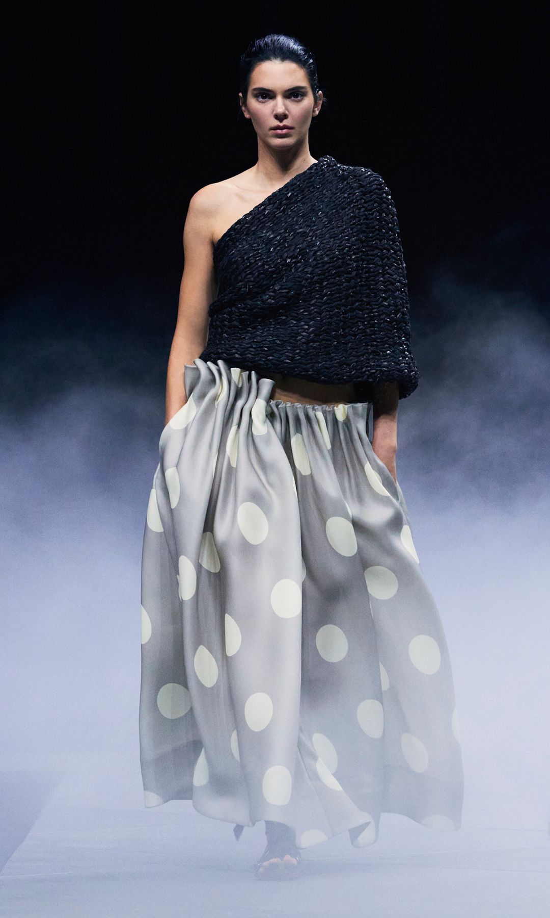Kendall Jenner walks the runway in an oversized grey skirt covered in white polka dots and a one-shouldered black top