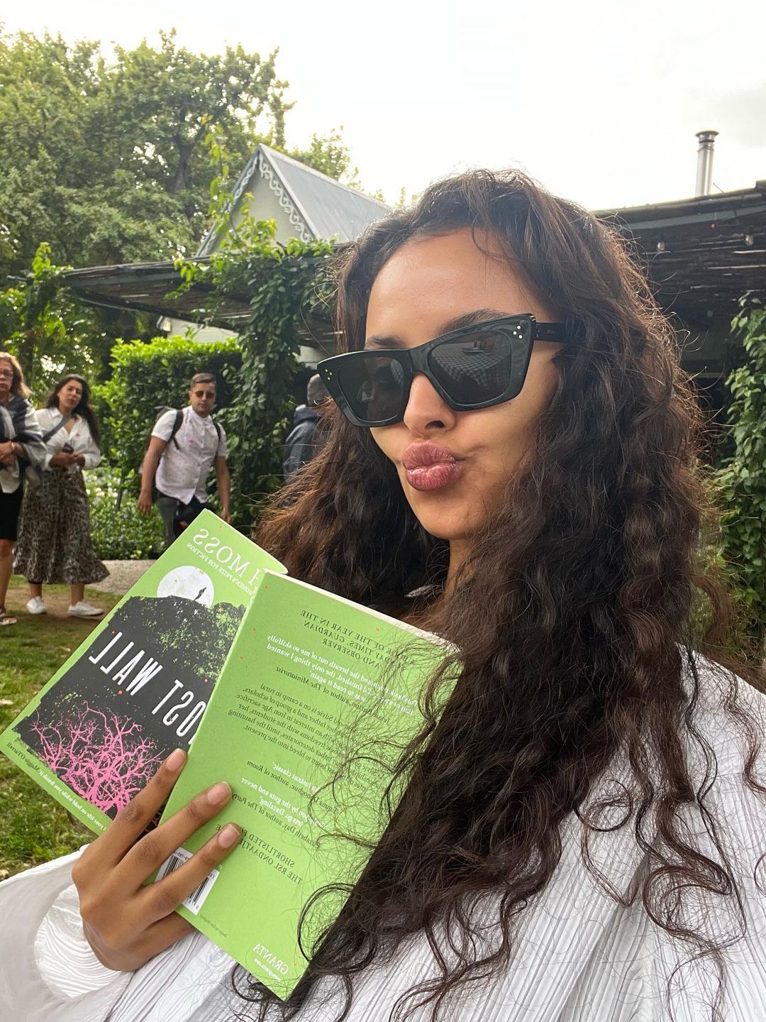 Maya Jama wears a pair of black sunglasses to read a book under a tree in South Africa